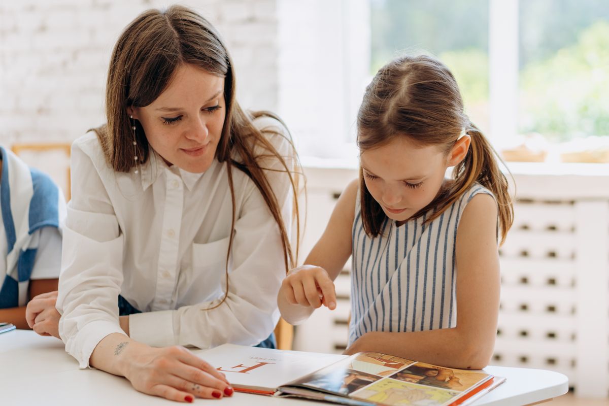 Tutor helping a young learner read at home